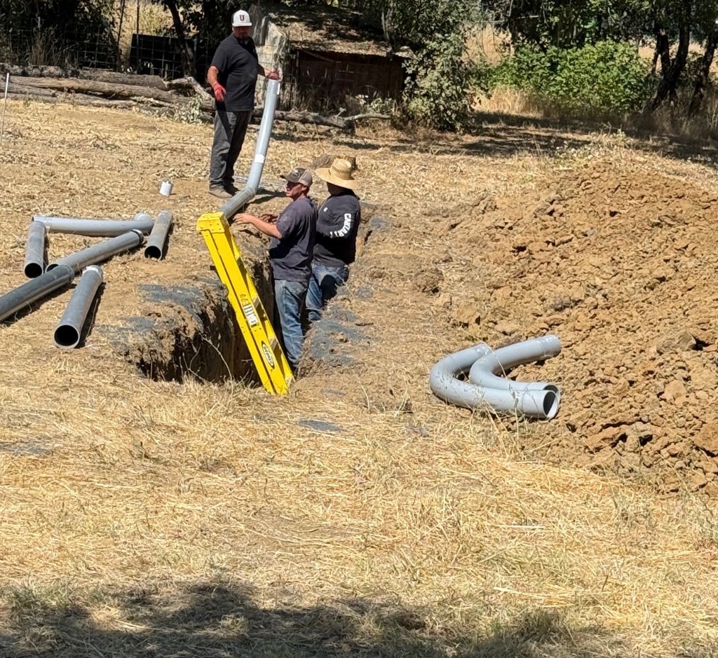 Crew installing underground conduit in a trench